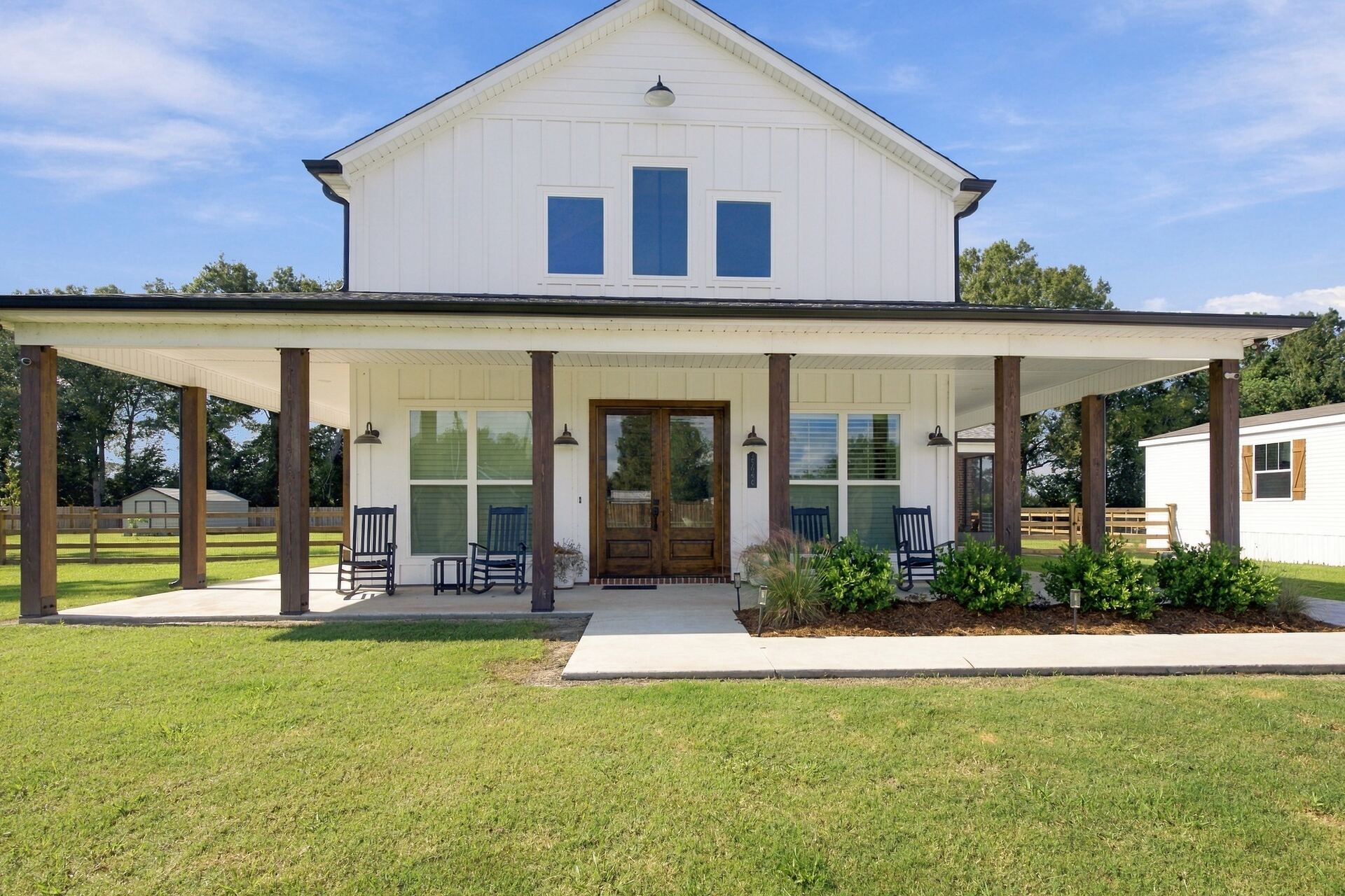 Front elevation of a white board-and-batten farmhouse with wraparound porch