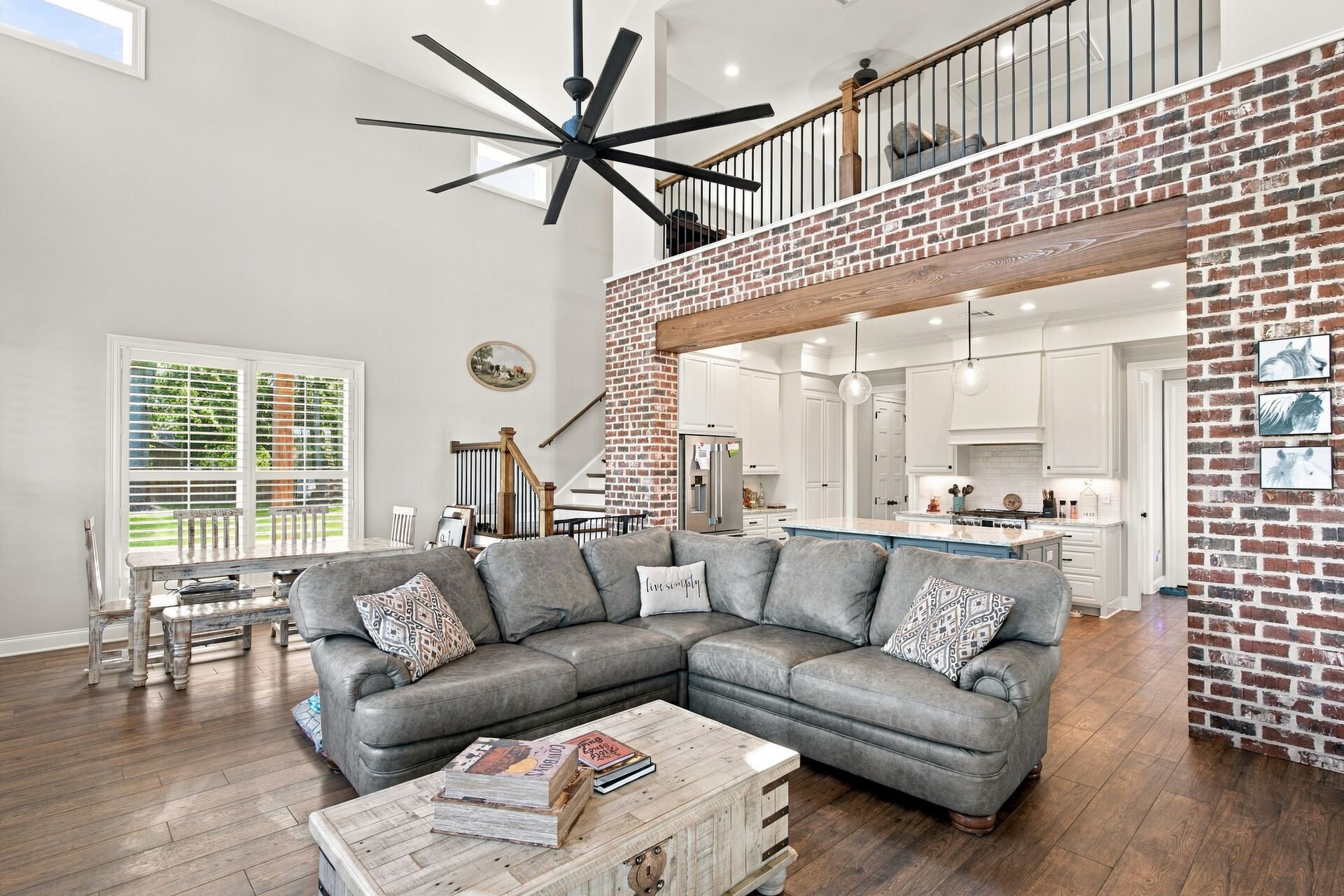 Two-story great room with exposed brick and open kitchen beyond