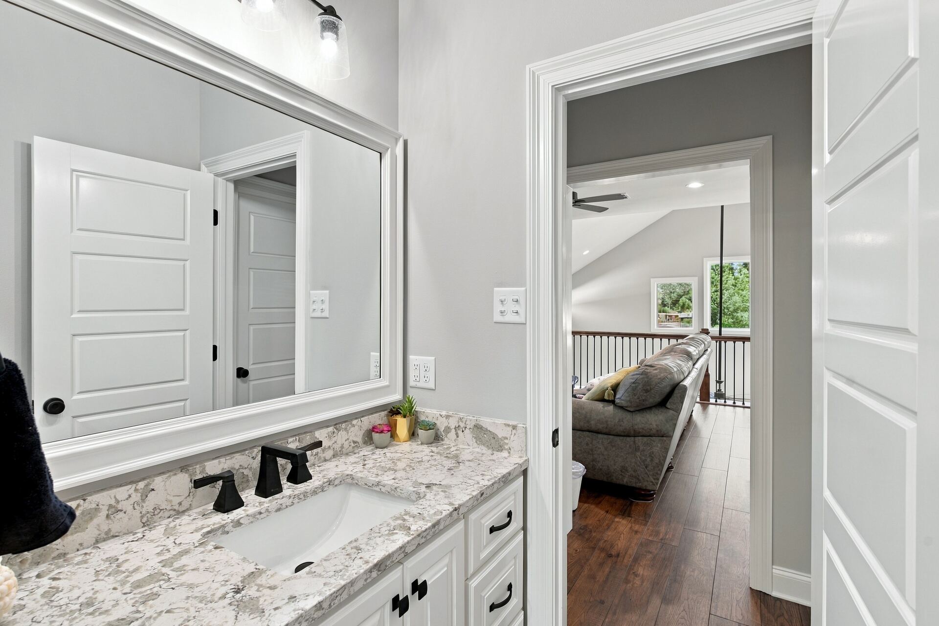 Bathroom vanity with a large mirror, bedroom visible beyond